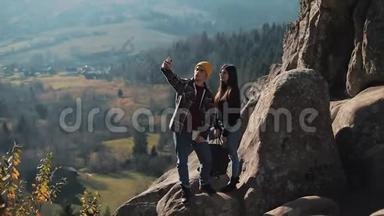 恋爱中的年轻夫妇站在岩石上，拍了一张自拍肖像。 拜访著名游客的男人和女人